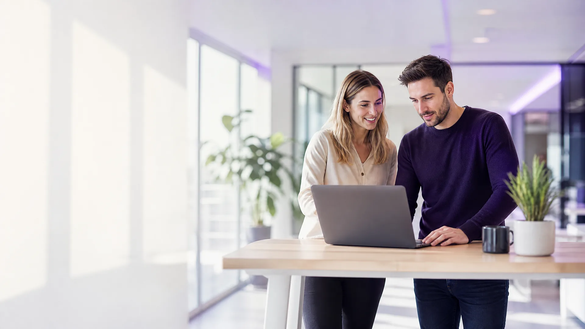 Twee collega's bekijken samen ICT-diensten voor bedrijven op een laptop in een licht kantoor